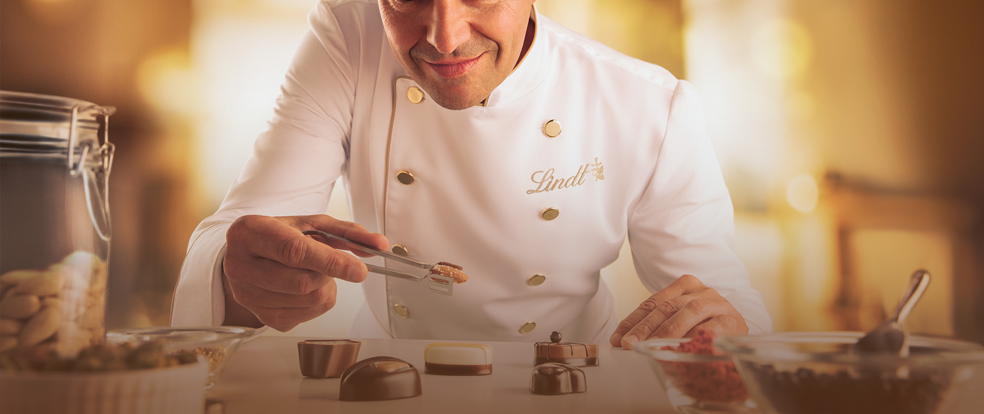 Maître chocolatier Urs Liechti decorating truffles holding an almond in pincers (Photo)